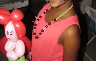 A Little Girl in a Beaded Necklace With a Balloon