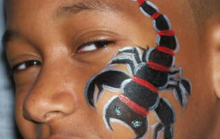 A Boy With a Black Color Scorpion on Face