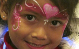 A Little Girl With Pink Color Heart Painting on Face