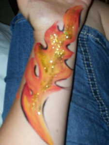 A Flame Painted on an Arm With Glitters