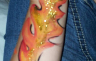 A Flame Painted on an Arm With Glitters
