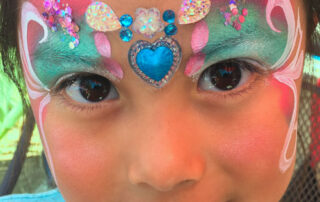 A Little Girl With Face Painting With Stones