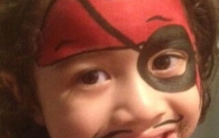 A Little Boy With a Pirate Face painting in Red Color
